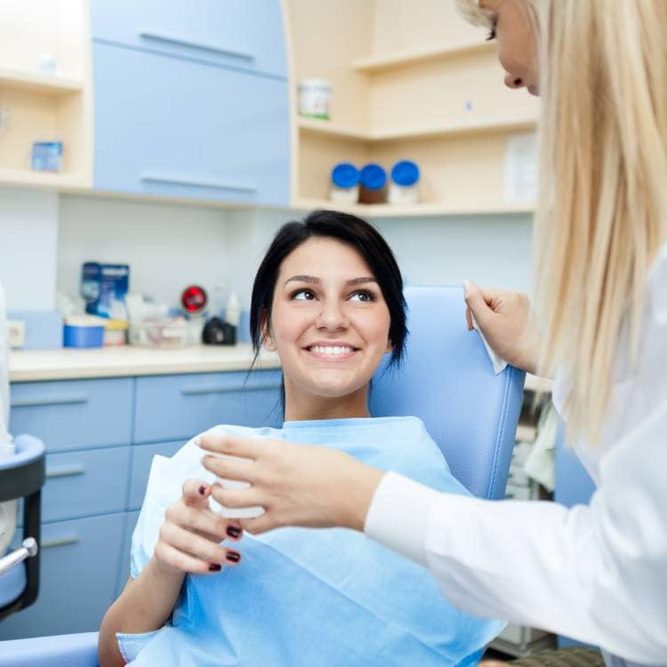 Pacientka s úsmevom komunikuje s dentálnou hygieničkou.