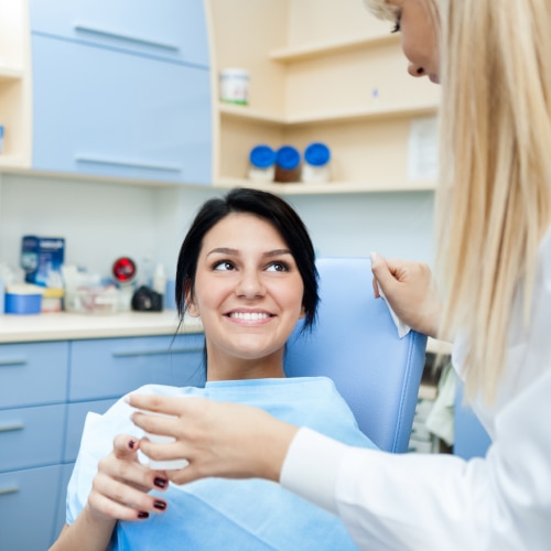 Pacientka s úsmevom komunikuje s dentálnou hygieničkou.