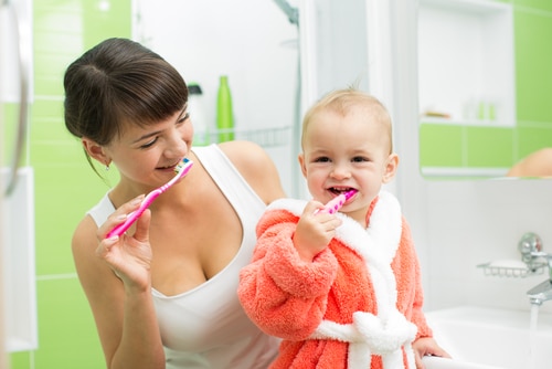 mother with baby brushing teeth in bathroom